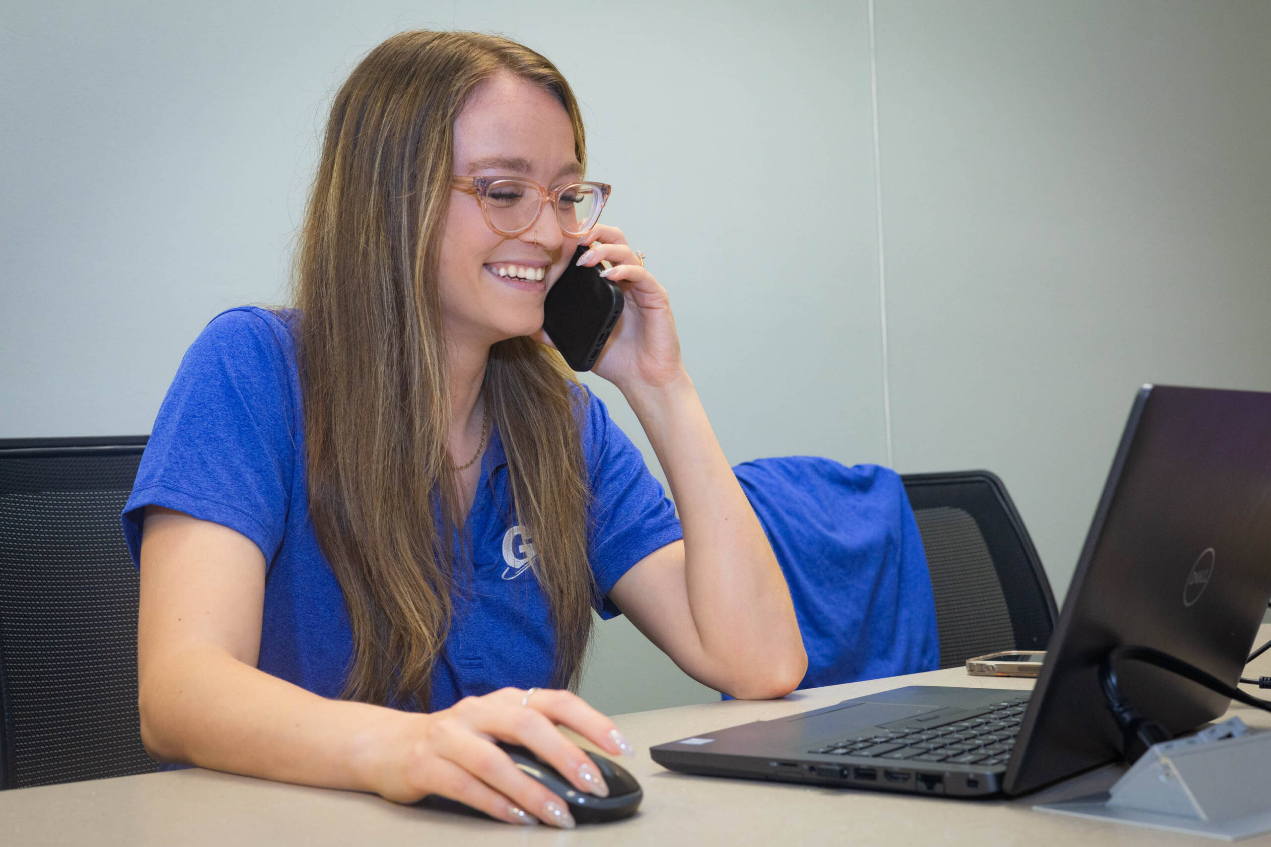 woman talking on the phone and looking at a laptop