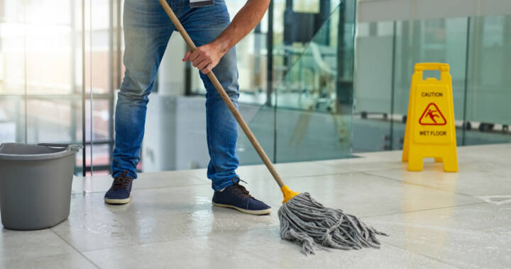 Shot of an unrecognizable man mopping the office floor
