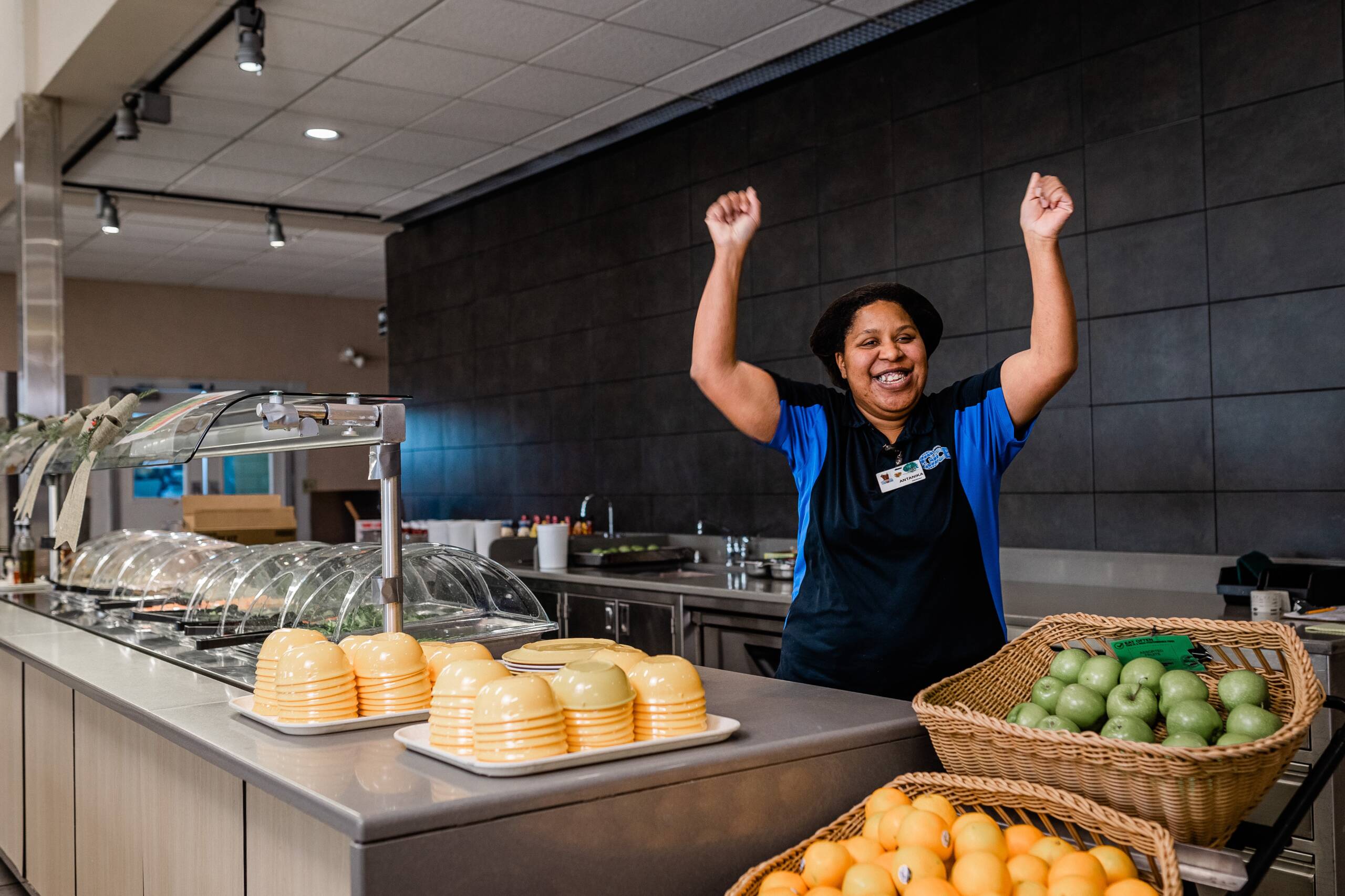 Antanika Doukkali standing in a cafeteria smiling with her hands up