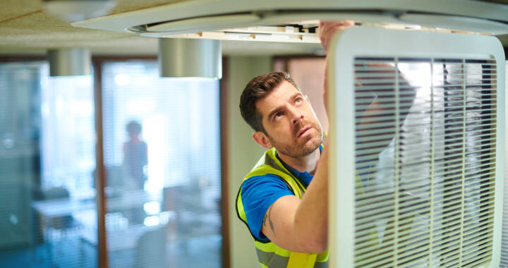 Facilities maintenance worker repairing a light in an office building