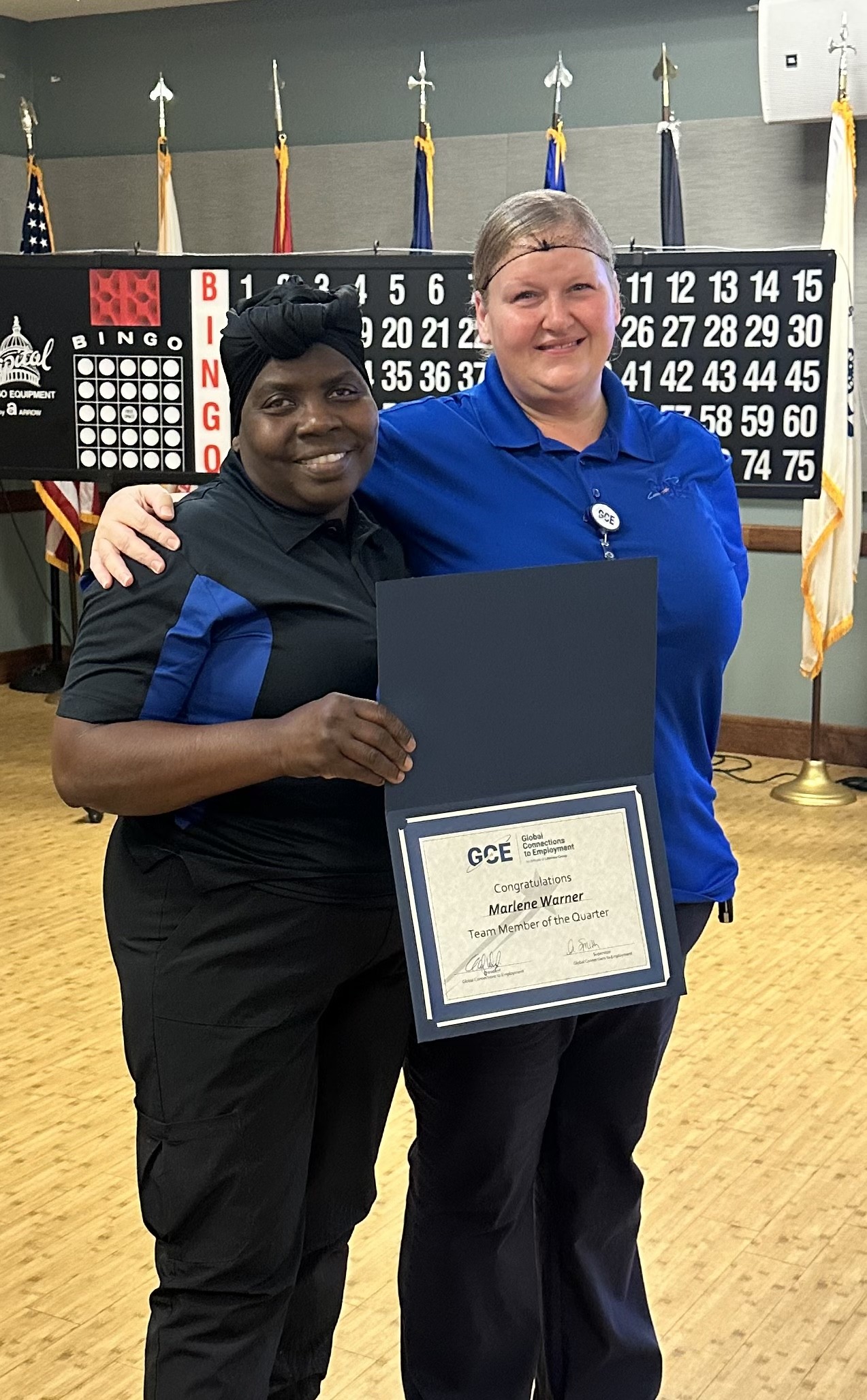 This photo shows Marlene Warner on the left and Project Manager Ann Smith on the right. Marlene is holding her certificate. Ann has her arm around Marlene's shoulder. Both are smiling.