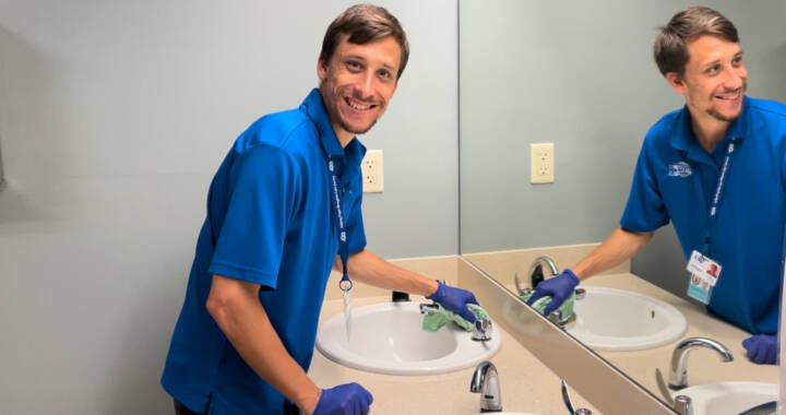 Custodial worker wiping bathroom sink