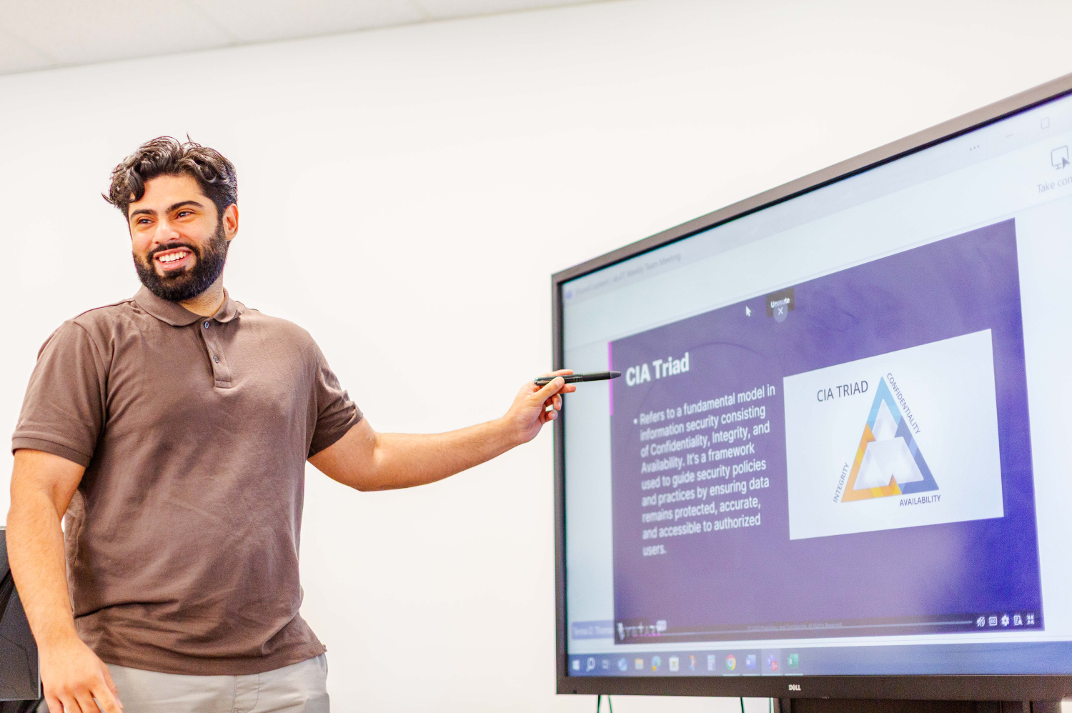 Man smiling pointing at computer screen, leading a training class